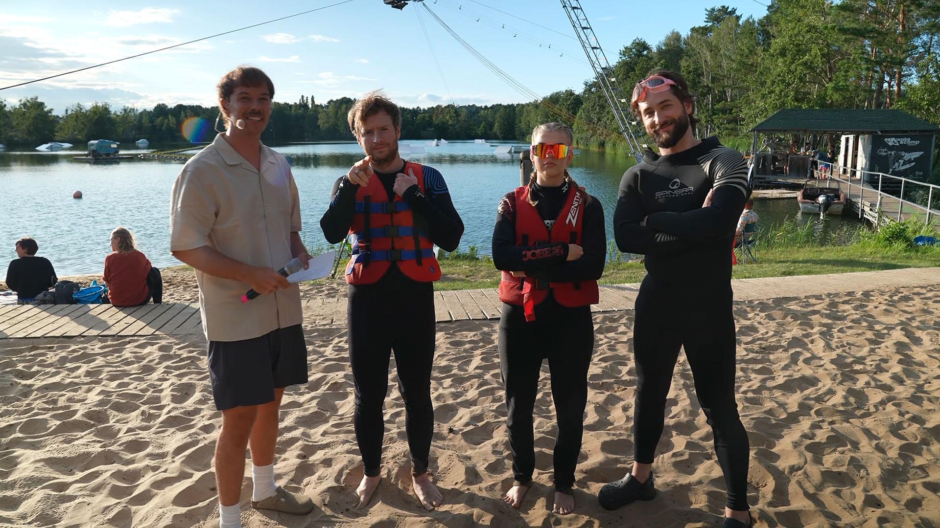 "Streamergarten - Folge 1: Das Wasser-Rodeo": Die Streamer Fibii (2.v.r.), Maxim (2.v.l.) und Pascalis (r.) stehen in Neopren-Anzügen mit Host Aditotoro (l.) vor dem Streamergarten-See.