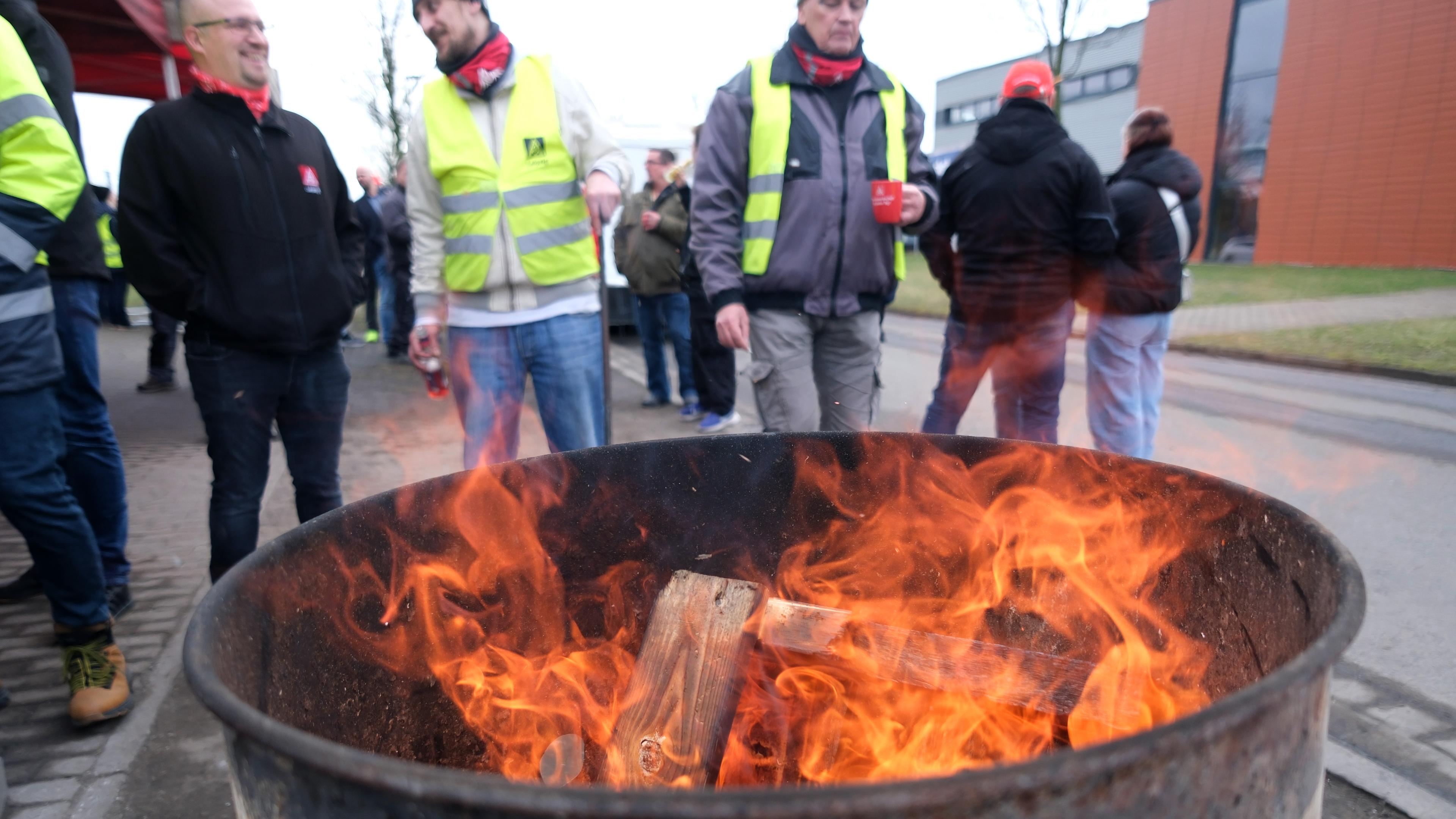 Beschäftigte des Recyclingbetrieb SRW metalfloat stehen an einer Feuerstelle, aufgenommen am 15.02.2024 in Espenhain (Sachsen)