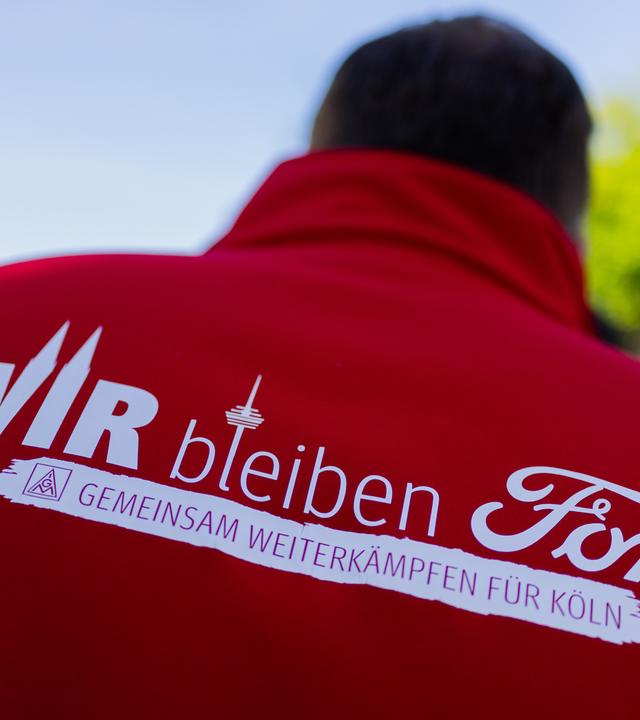 Ein Mitarbeiter trägt eine Jacke mit der Aufschrift Wir bleiben Ford - Gemeinsam weiterkämpfen für Köln beim ersten Streik der Geschichte vor den Kölner Ford-Werken.