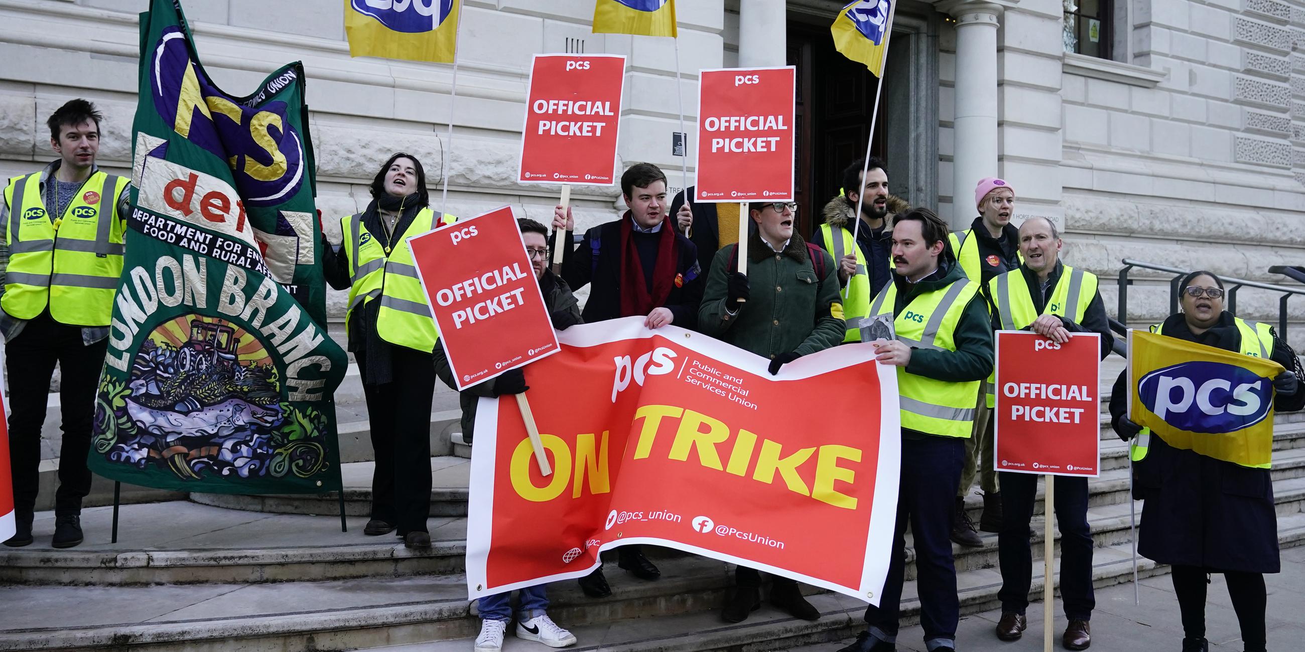 Mitglieder der Gewerkschaft für öffentliche und kommerzielle Dienste (PCS) stehen an einem Streikposten vor dem Büro des britischen Finanzministeriums. 