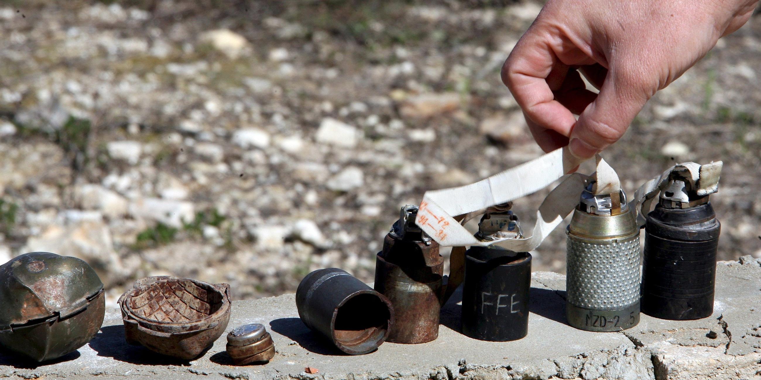 Verschiedene Arten von nicht explodierten Streubomben und Minen stehen aufgereiht nebeneinander, aufgenommen im Libanon. 