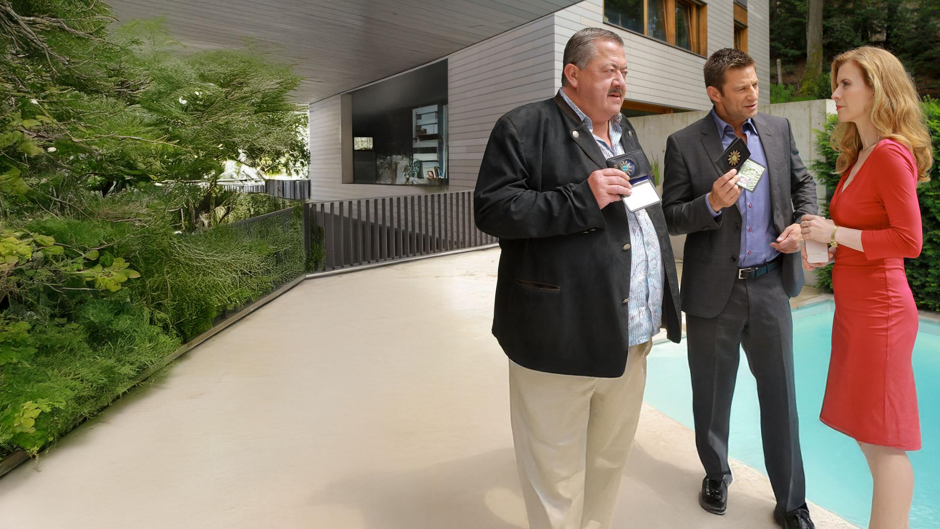 "Die Rosenheim-Cops - Nach Strich und Faden": In ihrem Garten wird Claudia Kaiser (Evamaria Salcher) von den Kommissaren Hofer (Joseph Hannesschläger) und Hansen (Igor Jeftic) befragt. Die Kommissare halten ihre Dienstmarken in den Händen.