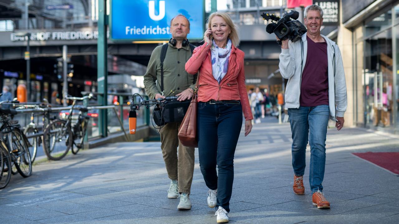 ZDF-Landesstudio-Redakteurin Stefanie Hayn und Kamerateam laufen auf der Berliner Firedrichsstraße.