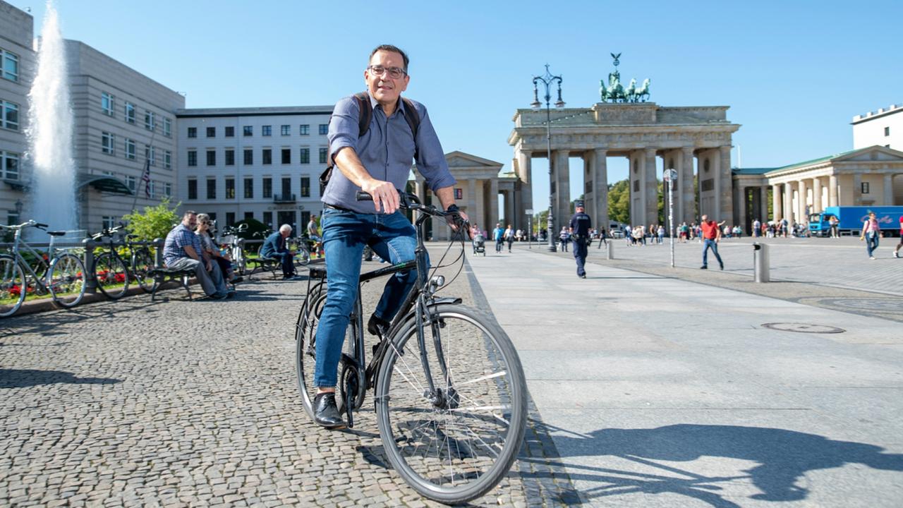 Landestudioleiter Stephan Merseburger auf dem Fahrrad vor dem Brandenburger Tor.