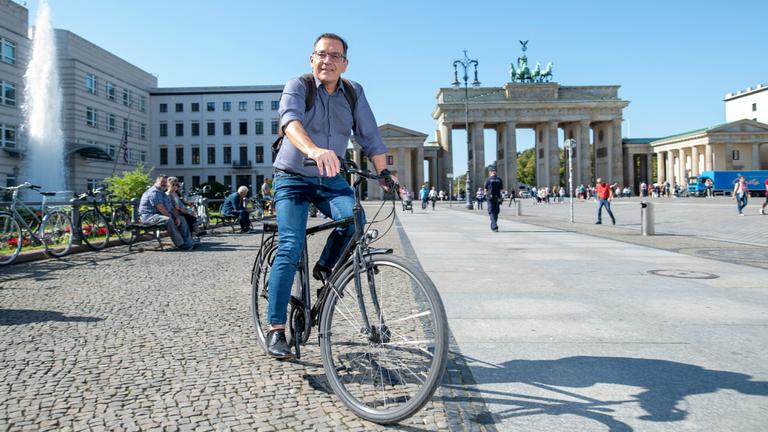 Landestudioleiter Stephan Merseburger auf dem Fahrrad vor dem Brandenburger Tor.