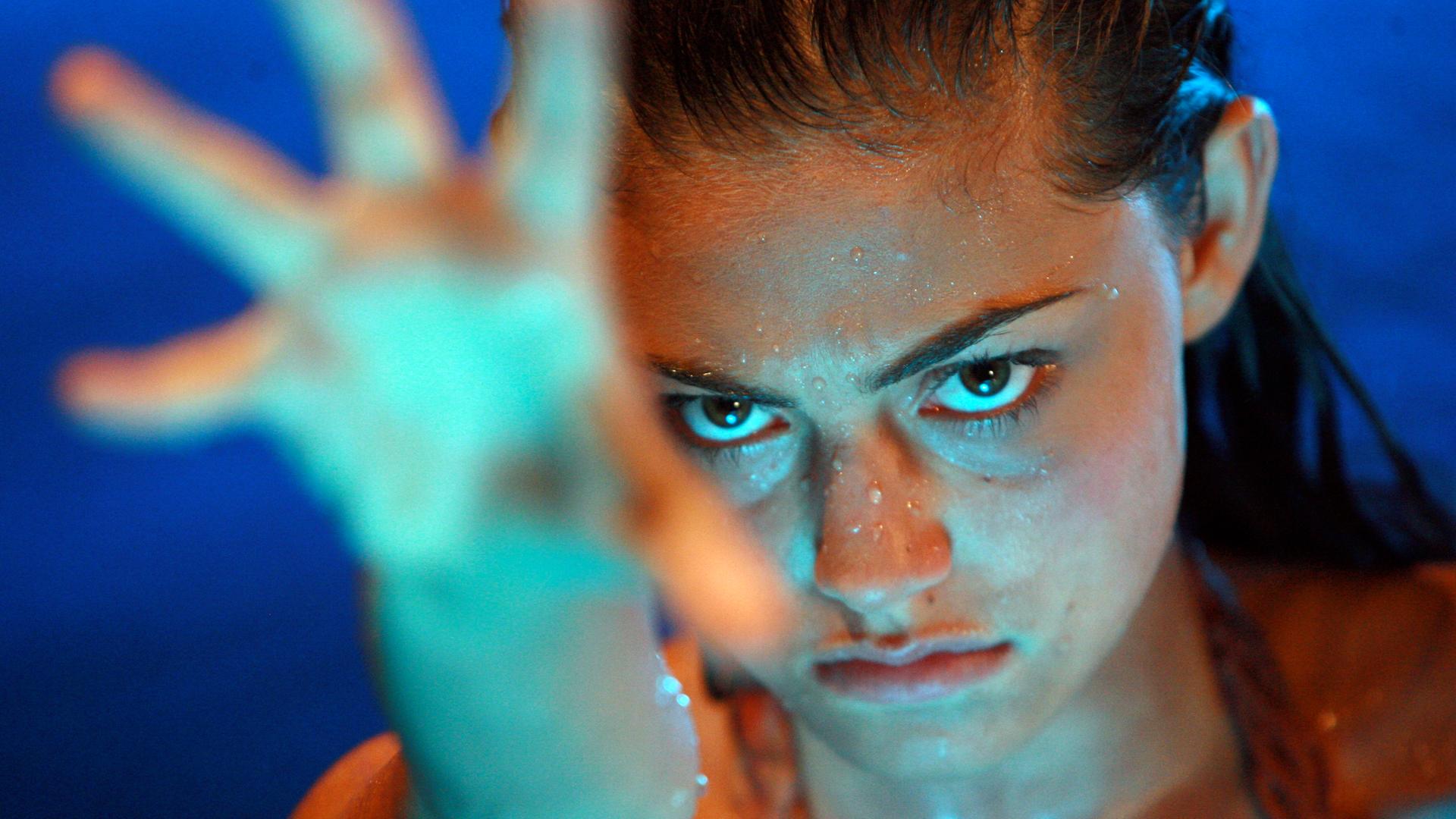 Cleo kämpft mit ihren magischen Kräften im Mondsee gegen den Vollmond. Sie streckt die Hand aus.