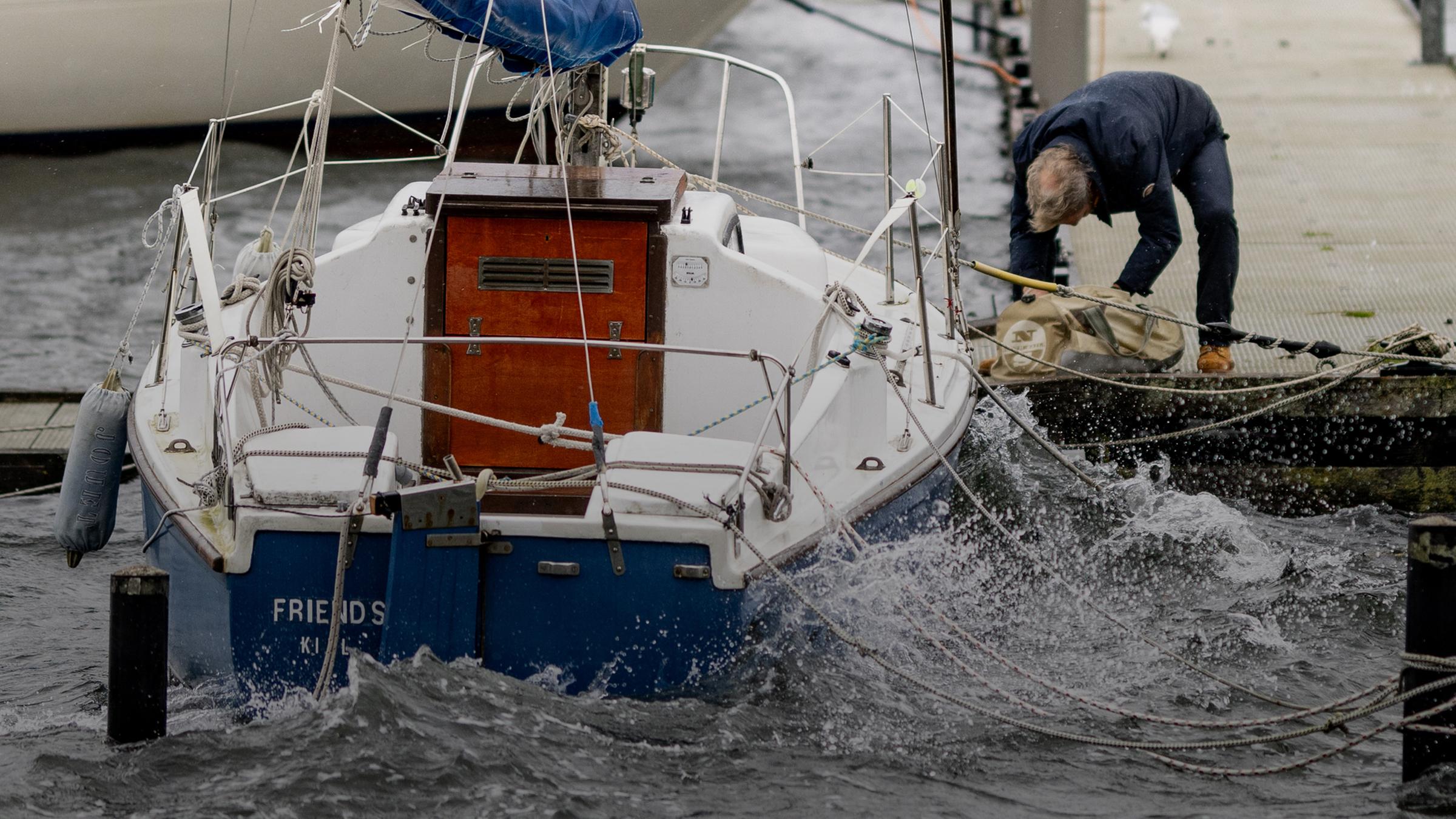 Ein Mann sichert am 19.10.2023 ein Segelboot an einem Anlegesteg an der Kieler Förde gegen eine erwartete Sturmflut.