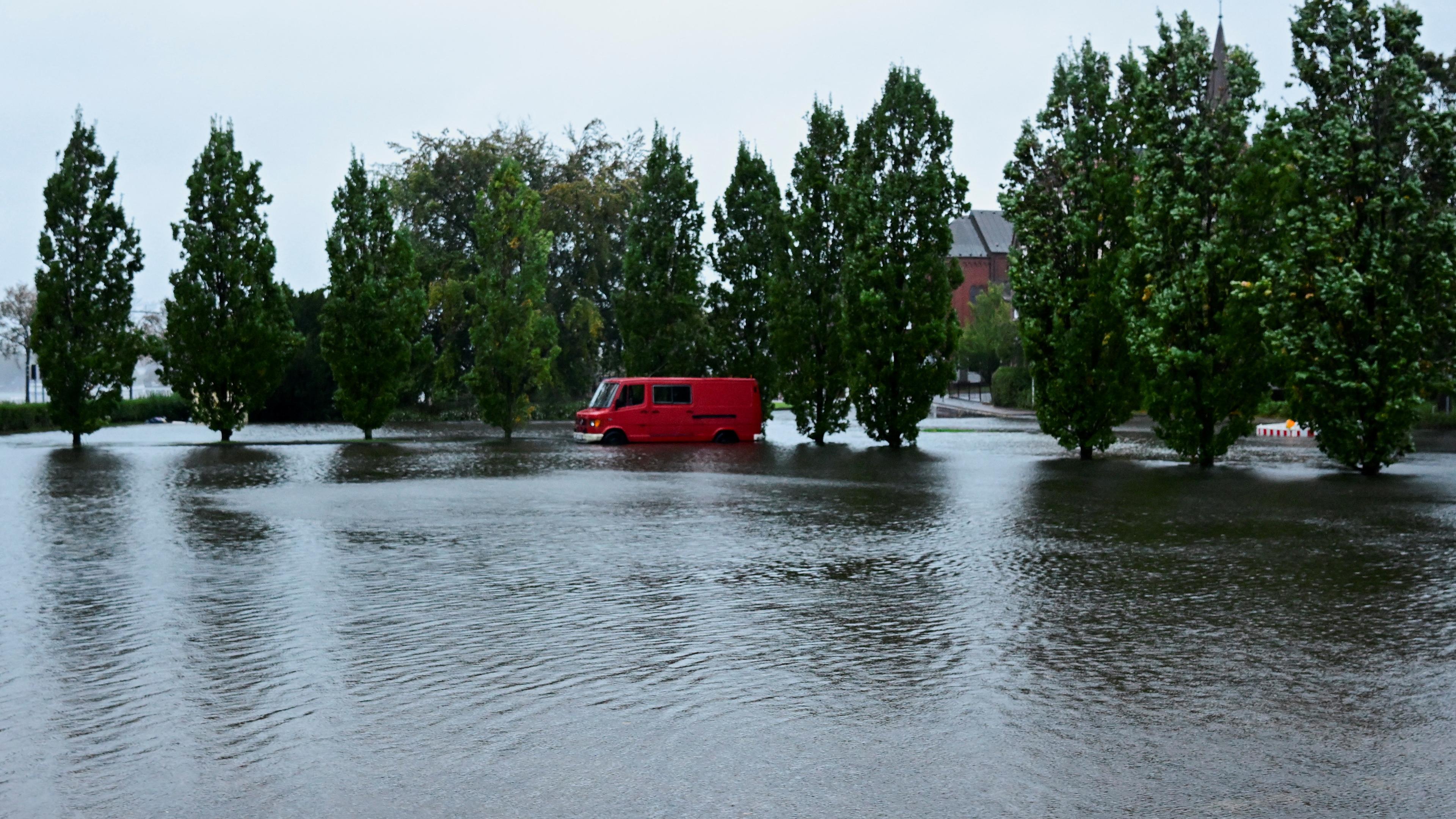 Ein Kleintransporter steht in Schleswig am Freitag in Norddeutschland auf einer überfluteten Straße.