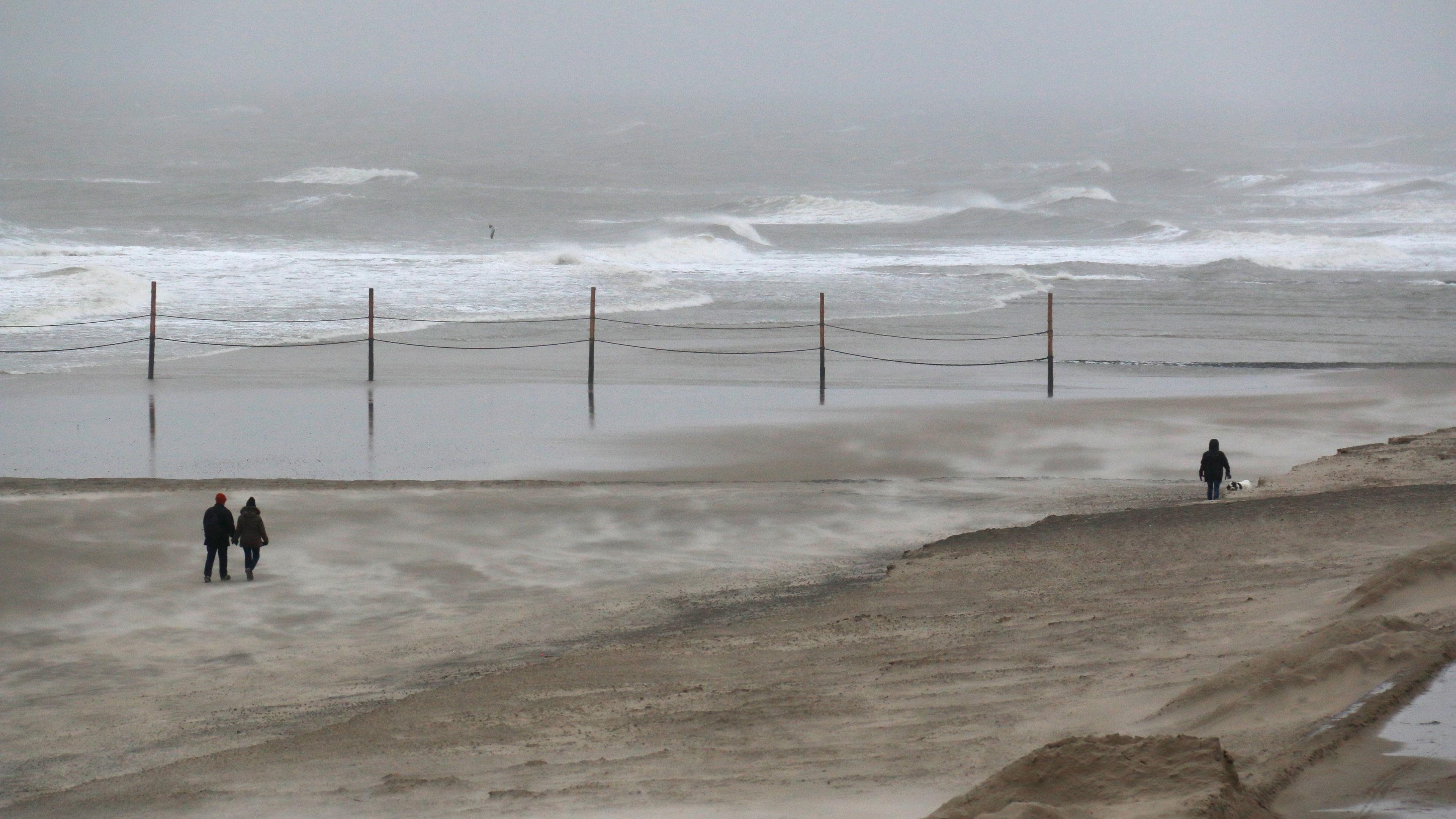 Strandspaziergänger trotzen dem Wind auf der Insel Wangerooge am 21.12.2023.