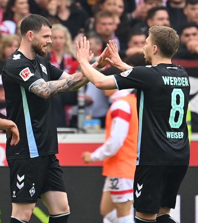 Bremens Oliver Burke und Mitchell Weiser jubeln nah dem Tor gegen Stuttgart beim Spiel am 13.04.2025.