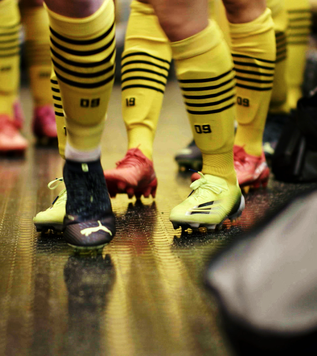 Unterschenkel von Fußballerinnen mit Fußballschuhen und gelb-schwarzen Stutzen des BVB