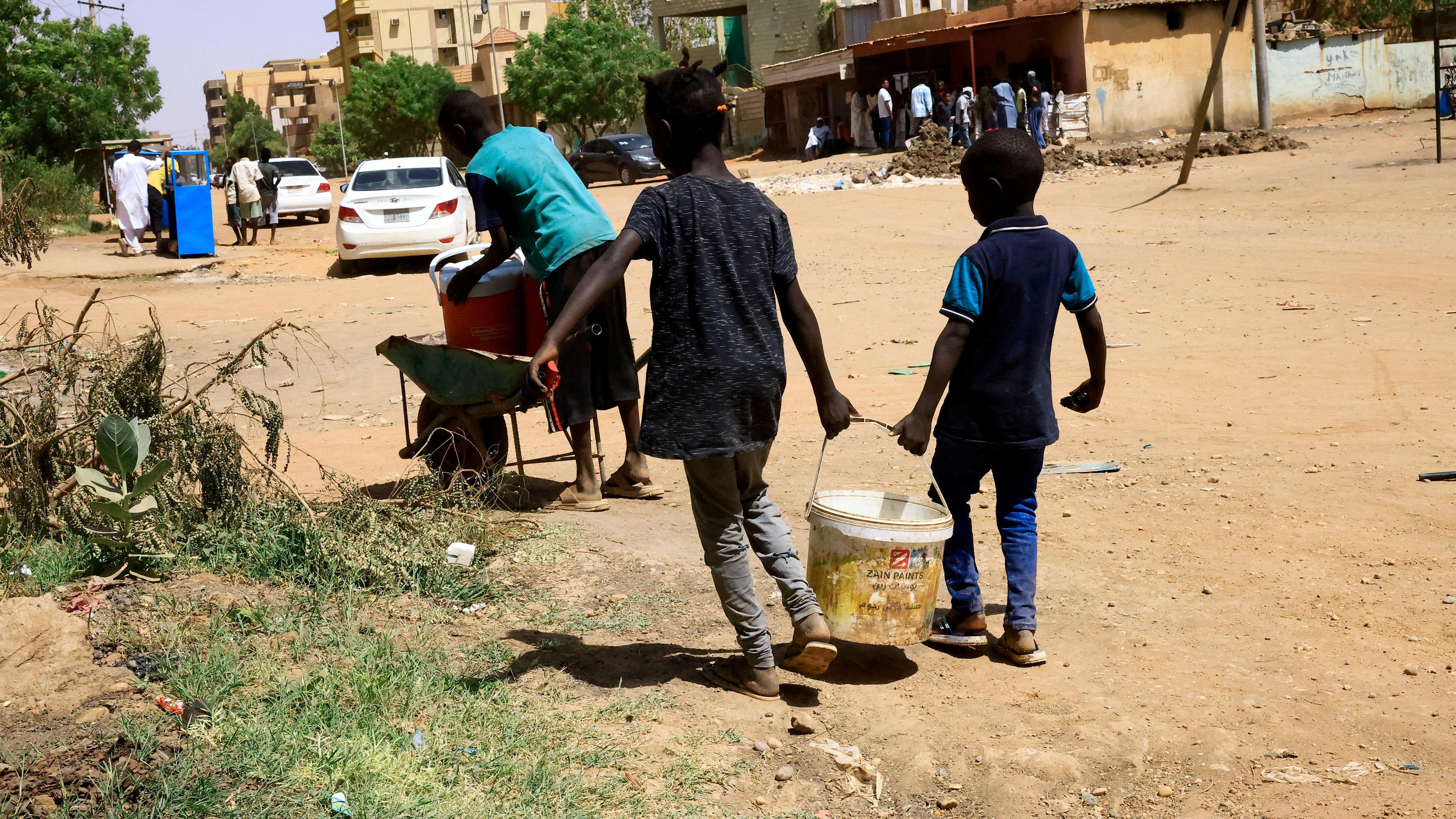 Kinder tragen im Sudan einen Eimer mit Wasser
