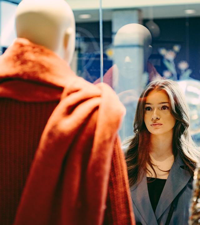 Sinem steht vor einem Schaufenster und schaut sich die Schaufensterpuppe an