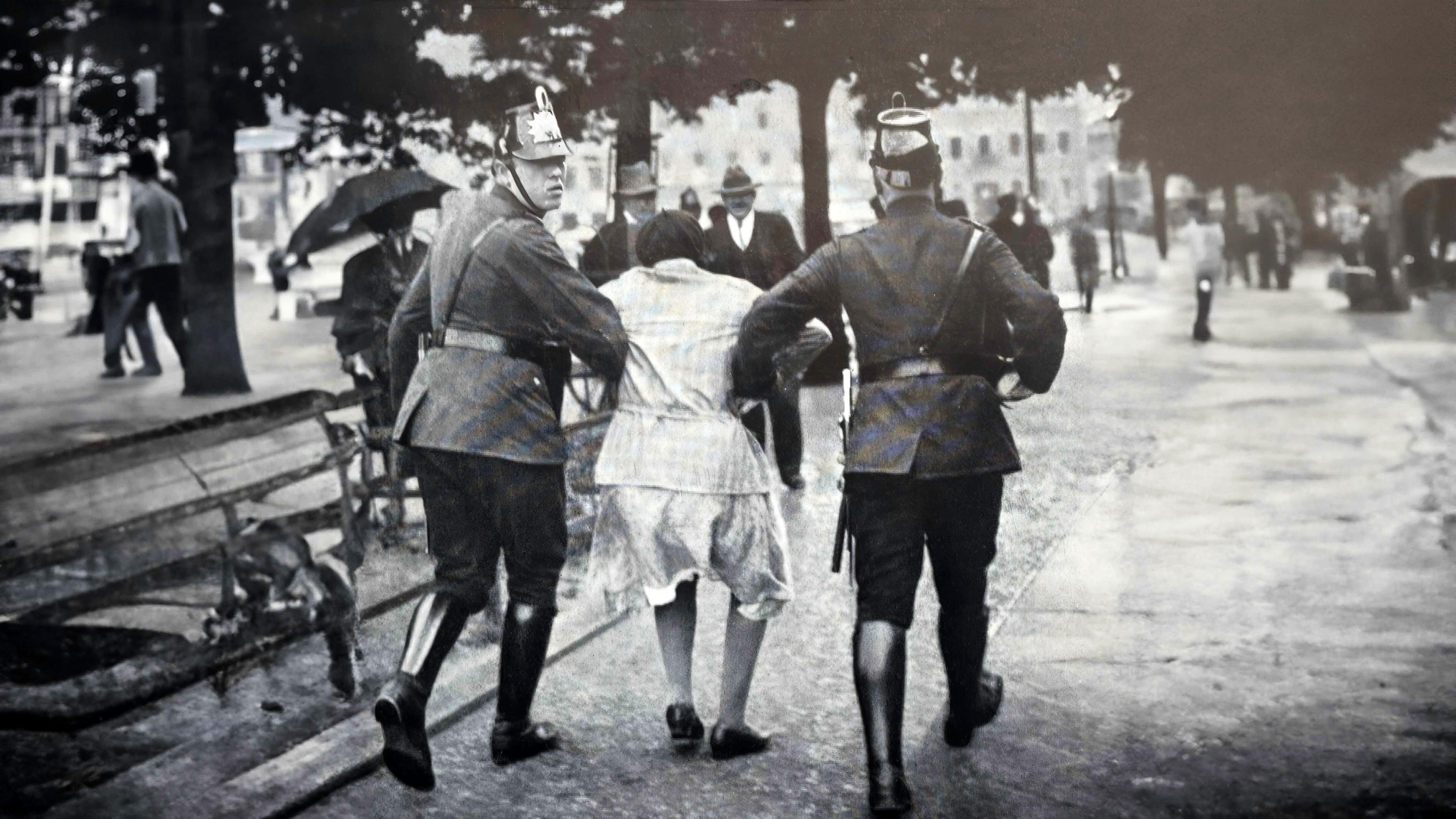 Schwarz-Weiß-Foto: Zwei Soldaten führen in ihrer Mitte eine Frau auf offener Straße ab.