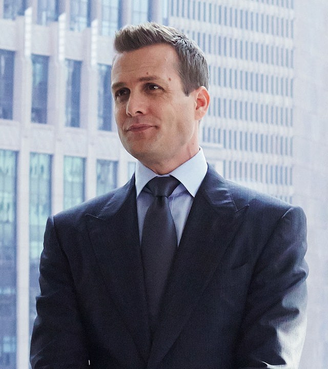 "Suits - Private Einsichten": Harvey (Gabriel Macht) steht im Anzug in einem Büro, lässig an ein Sideboard gelehnt. Hinter ihm sind große Fenster mit Blick auf die Skyline zu sehen.