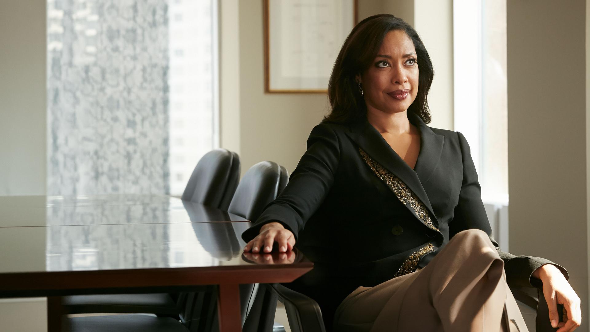 "Suits - Wie du mir, so ich dir": Jessica (Gina Torres) sitzt, elegant gekleidet, an ihrem Schreibtisch und schaut selbstbewusst nach vorne. Sie hat ihre rechte Hand auf den Schreibtisch gelegt.
