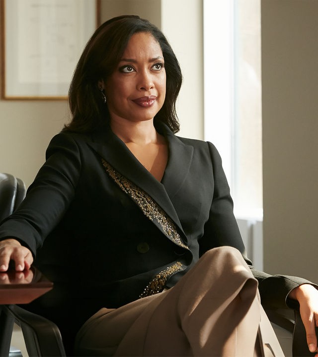 "Suits - Wie du mir, so ich dir": Jessica (Gina Torres) sitzt, elegant gekleidet, an ihrem Schreibtisch und schaut selbstbewusst nach vorne. Sie hat ihre rechte Hand auf den Schreibtisch gelegt.