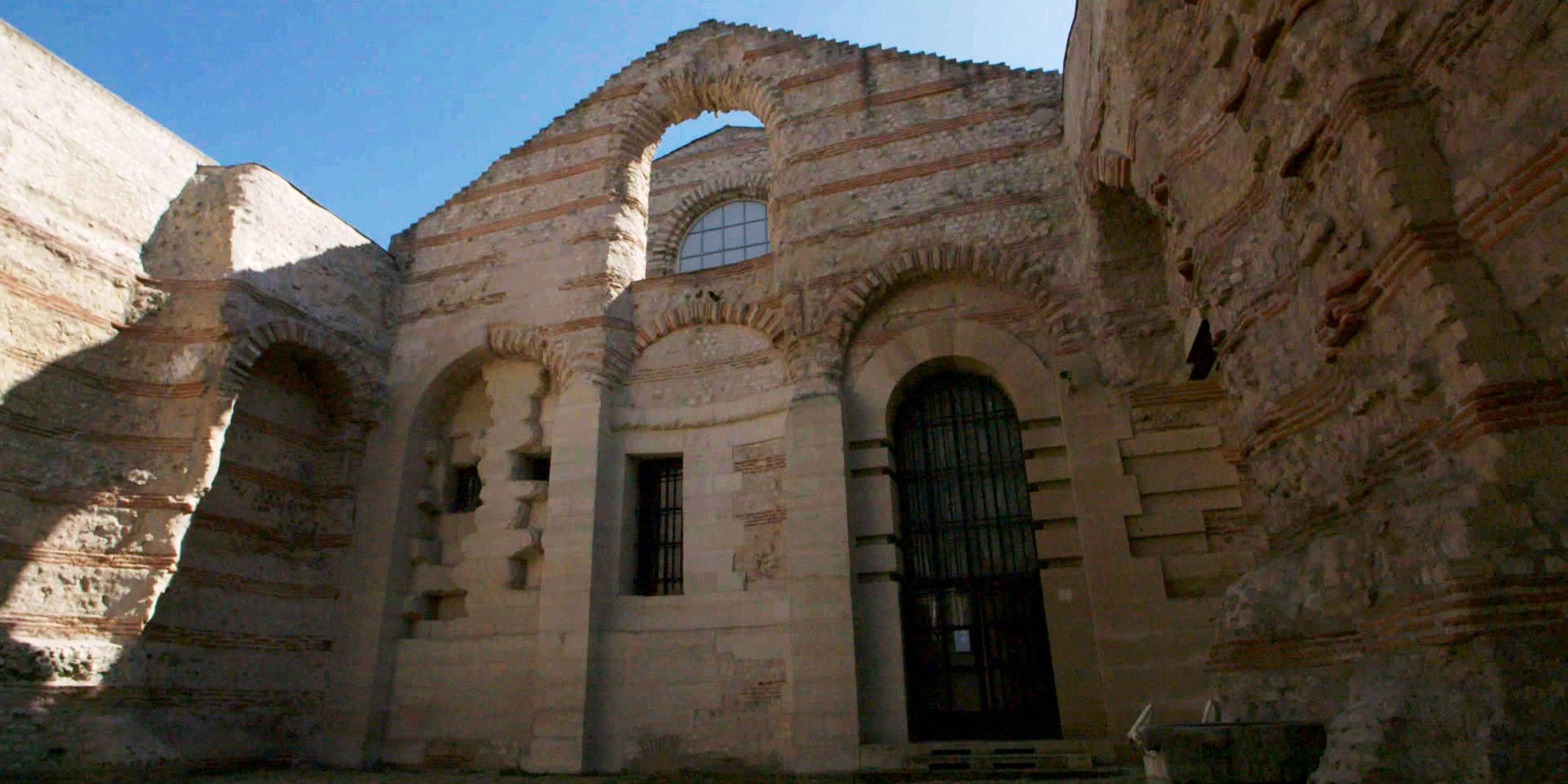 Drei Wände einer antiken Therme ohne Dach in der Untersicht.