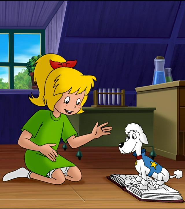 Superpudel Puck sitzt auf Bibis Mathebuch. Bibi sitzt ihm gegenüber.