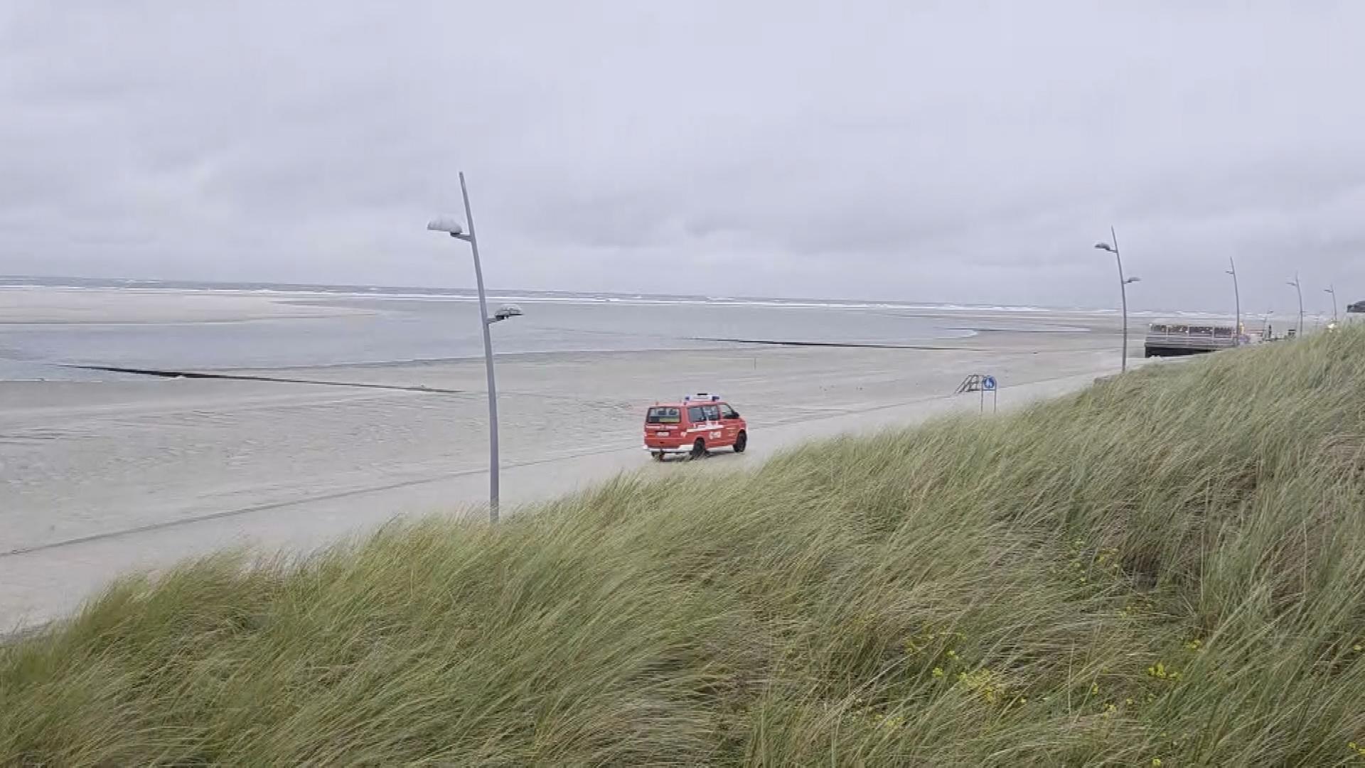 DLRG-Auto fährt am leeren Strand von Borkum bei einem Herbststurm.