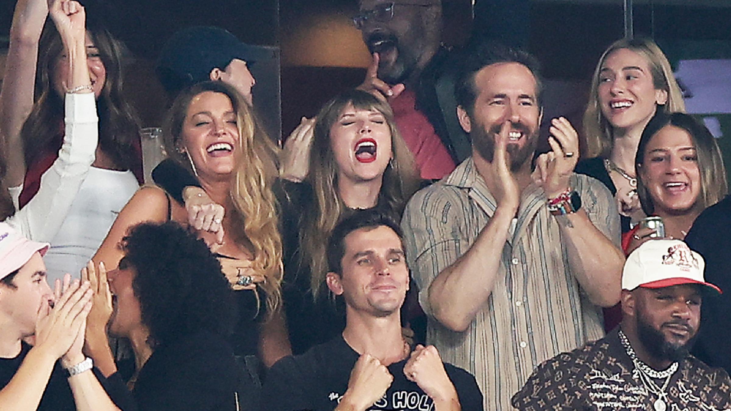 Taylor Swift, Blake Lively und Ryan Reynolds jubelnd auf einer Tribüne.