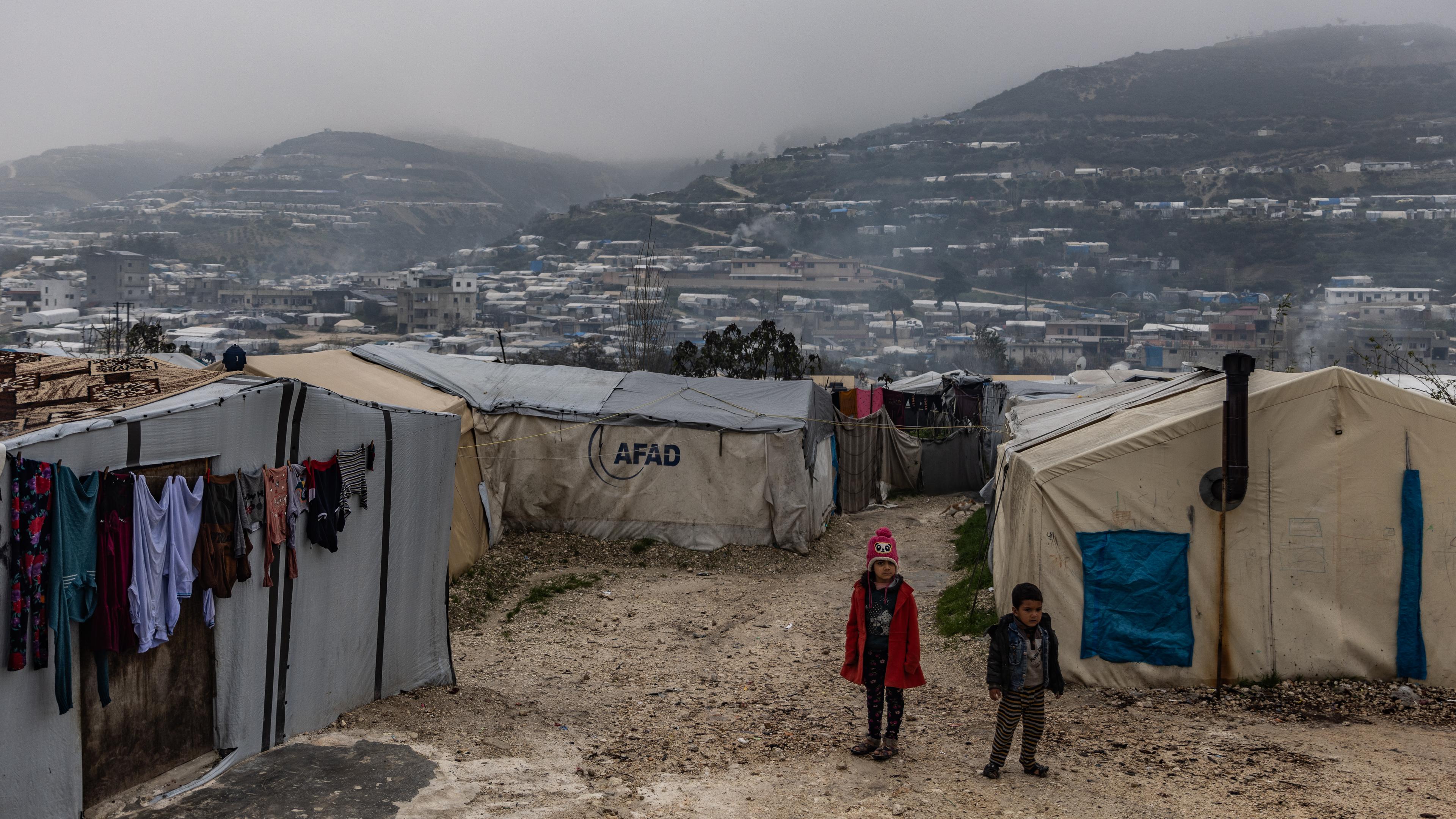 Flüchtlingslager in Syrien mit zwei Kindern vor Zelten