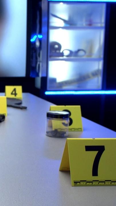 "Täterjagd - Der Fall Anne Barbot": Blick auf einen Indizientisch, auf dem mehrere Beweisstücke liegen. Im Hintergrund ist ein Foto von Anne Barbot zu sehen.