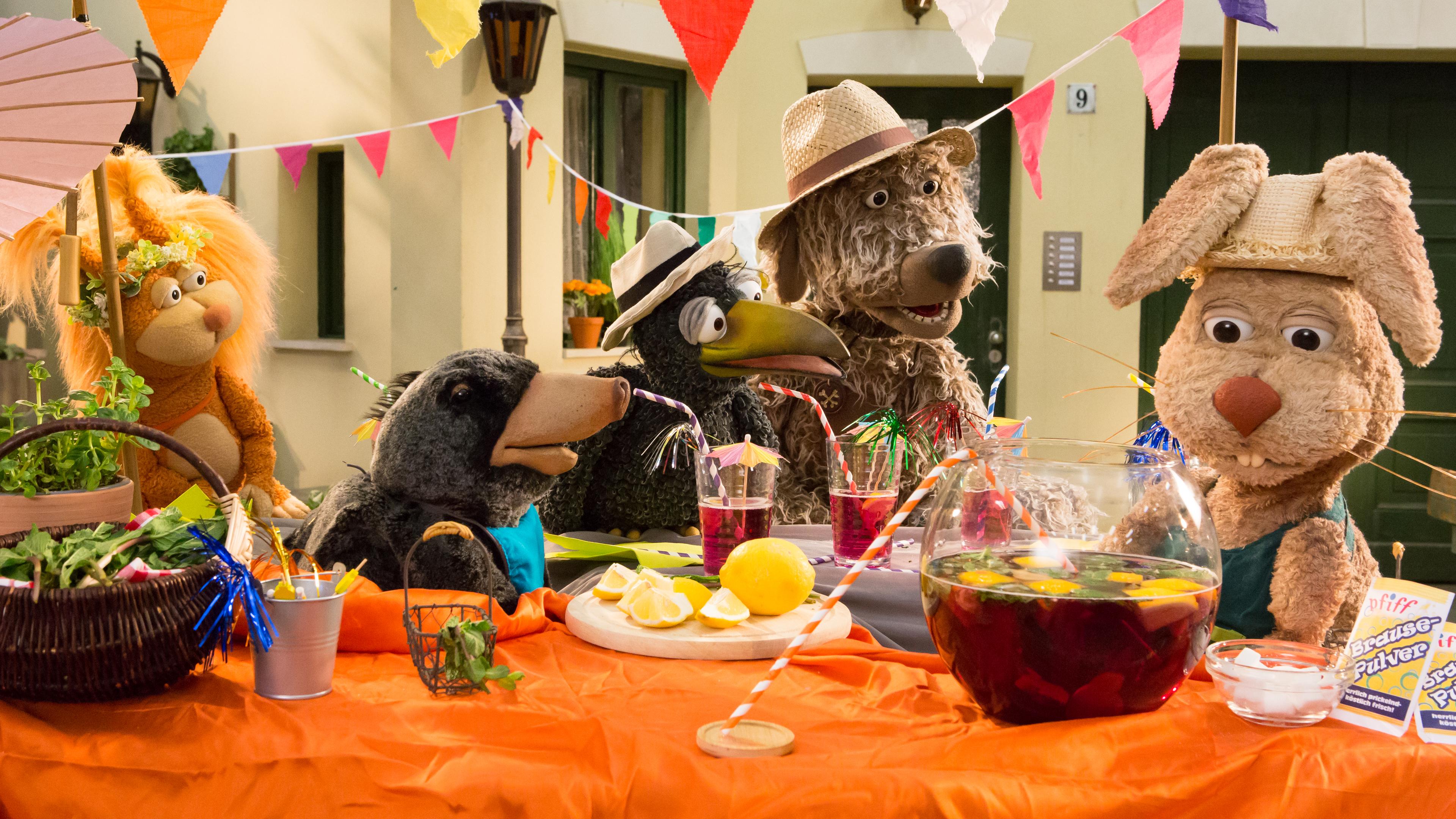 Die Freunde von Rudis Rasselbande stehen im Hof um einen Tisch versammelt. Alle schauen angespannt auf Otto, der wiederum ein mit Limonade gefülltes Bowleglas betrachtet.