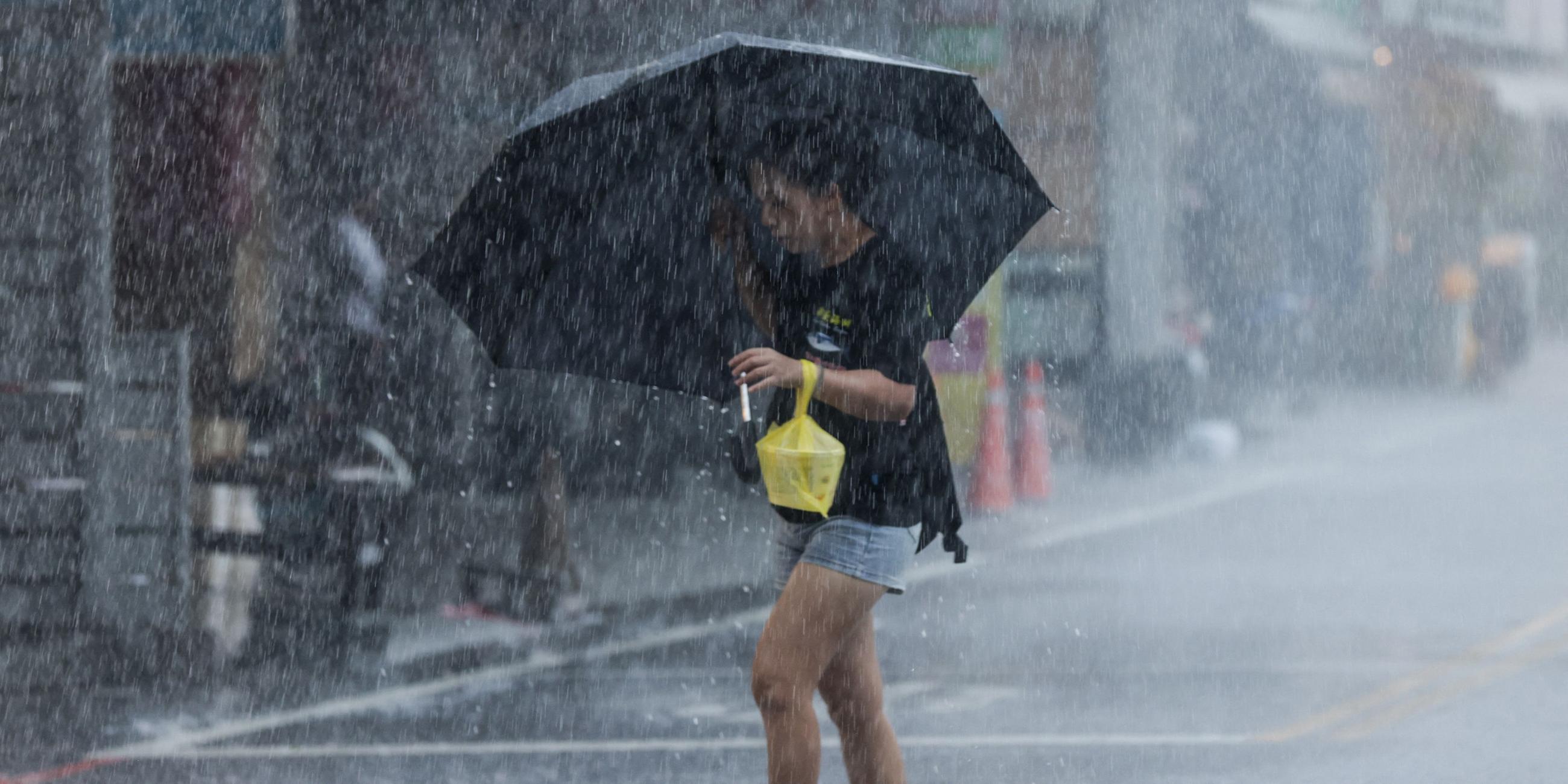 Eine Frau läuft mit einem Regenschirm bei starkem Regen in der Nähe des Hafens Su-ao in Yilan entlang