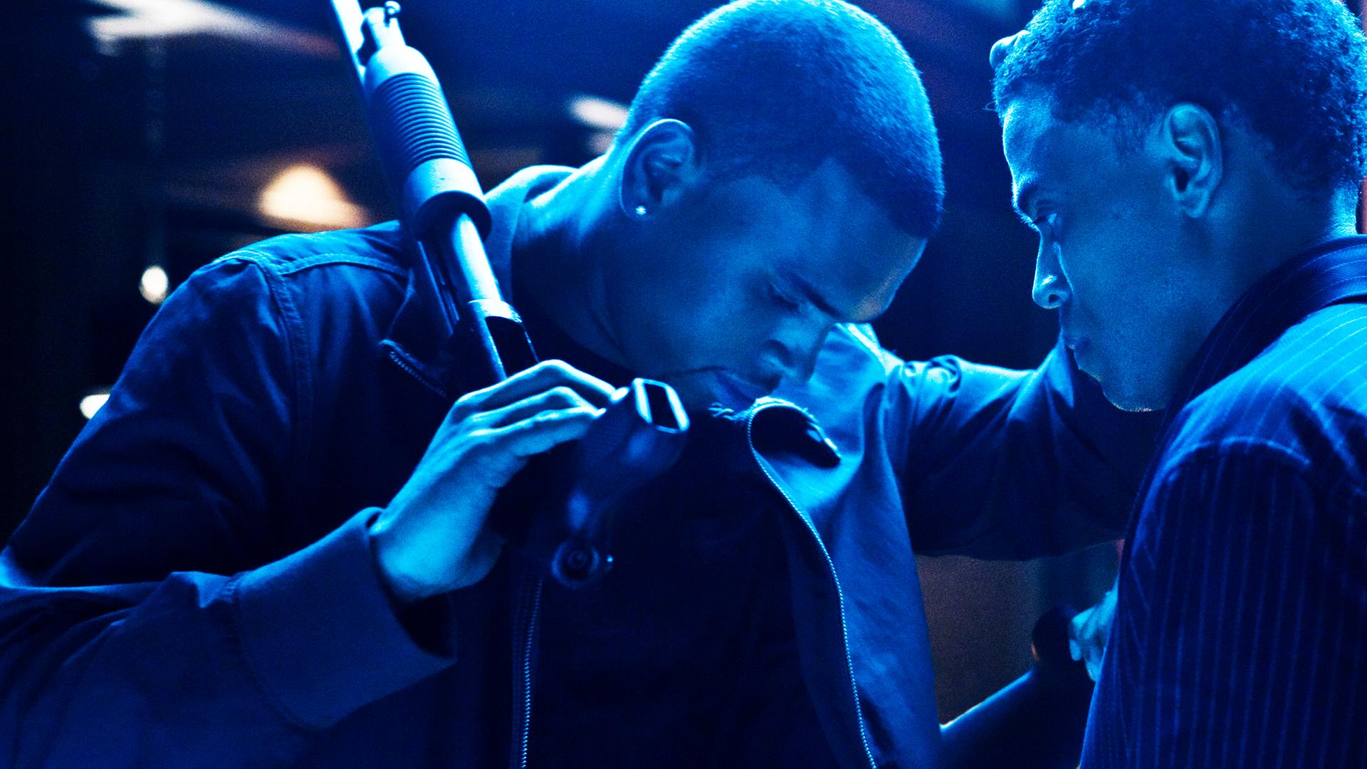 In bläulichem Licht hat Jesse (Chris Brown) ein Gewehr in der Hand und legt Jake (Michael Ealy) mit gesenktem Kopf eine Hand auf die Schulter.