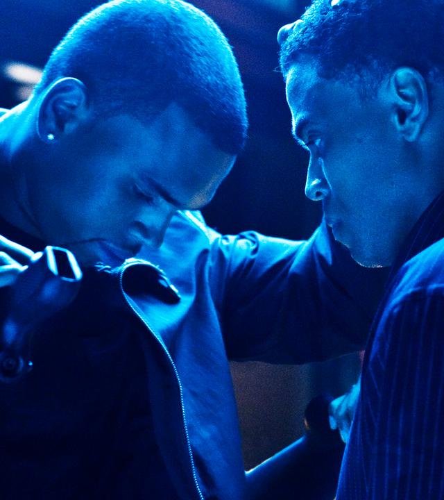 In bläulichem Licht hat Jesse (Chris Brown) ein Gewehr in der Hand und legt Jake (Michael Ealy) mit gesenktem Kopf eine Hand auf die Schulter.