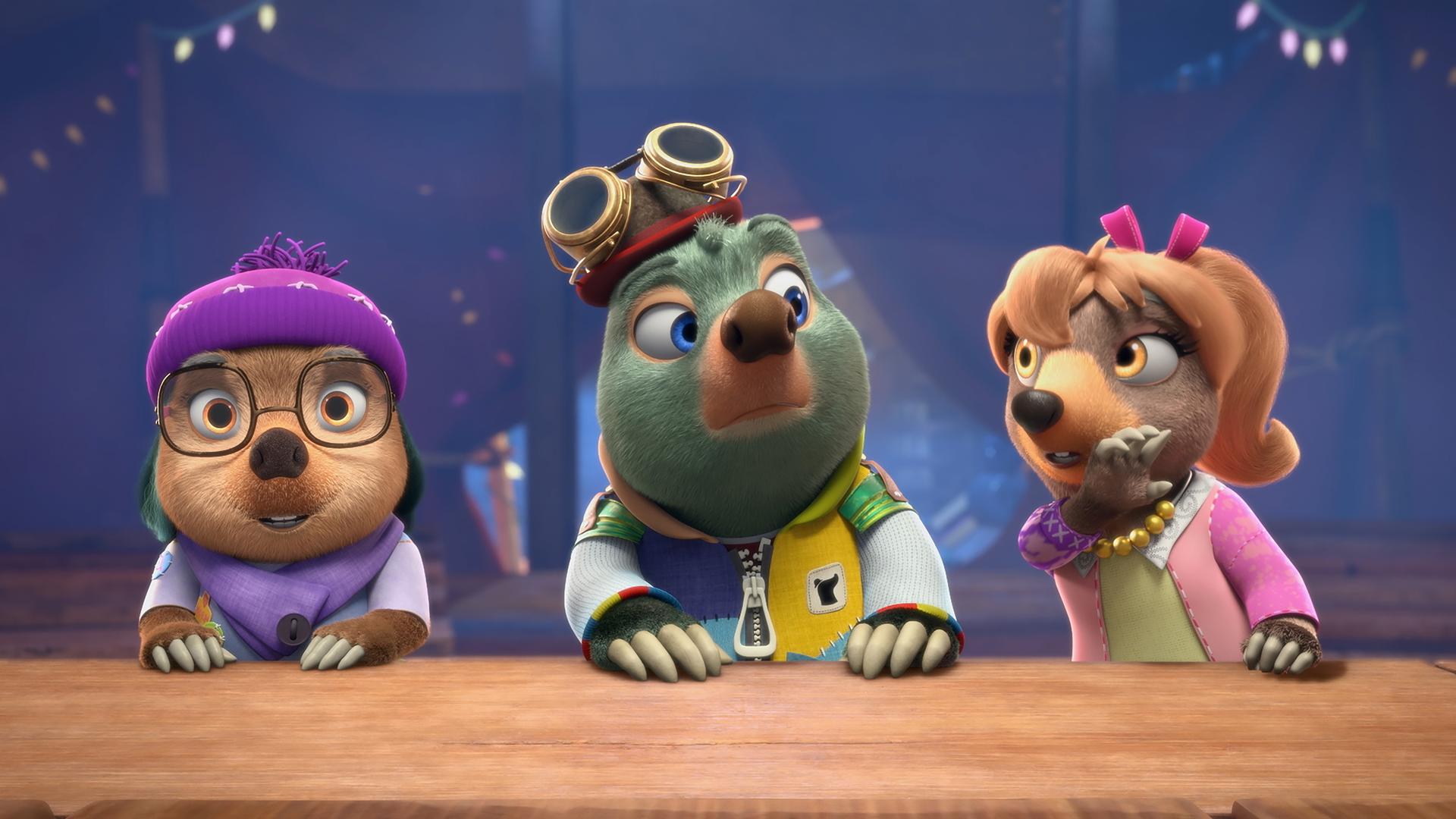 Vor blauem Hintergrund sitzen Dotty, Moley und Mona Lisa als Jury nebeneinander an einem Pult und betrachten mit kritischem Blick, was auf der Bühne präsentiert wird.