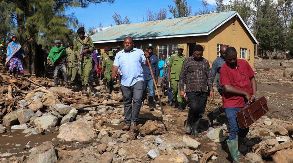 Premierminister Kassim Majaliwa läuft mit mehreren Personen über ein von Schlamm und Geröll bedecktes Gebiet