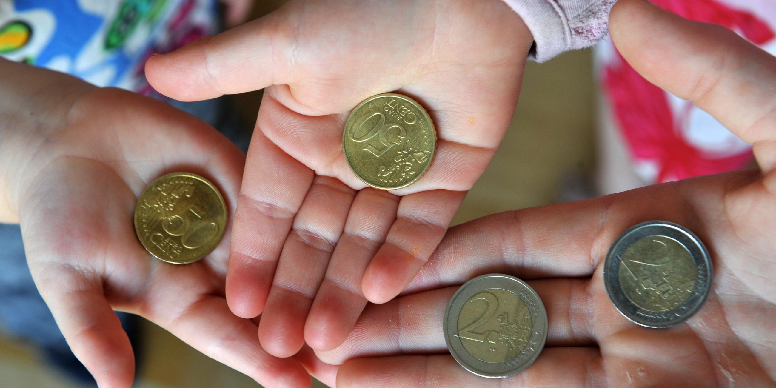 Drei Kinder halten ihr Taschengeld in den Händen