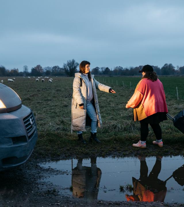 Miriam Peters steht neben ihrem Beratungsbus und reicht einer Frau die Hand.