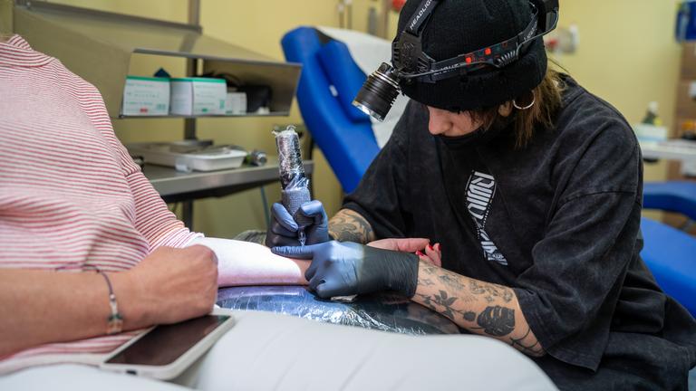 Eine Tätowiererin beim Aktionstag des Uniklinik Münster, tätowiert das Symbol der Organspende in einen Unterarm.