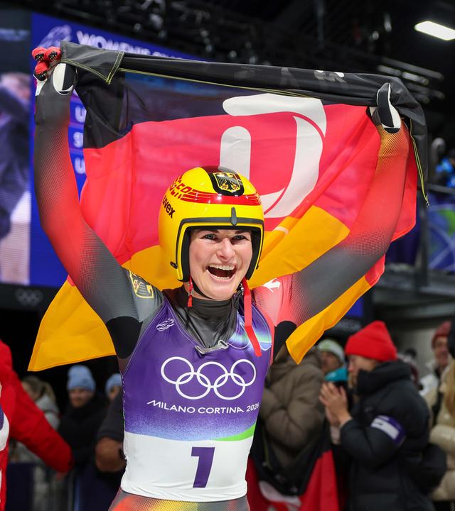 Olympiasiegerin Julia Taubitz feiert in Deutschlandfahne in der Hand ihren Olympiasieg.