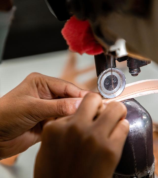 Großaufnahme von Händen, die an einer Nähmaschine nähen.