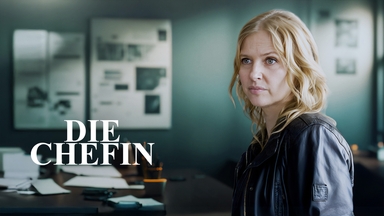 Die Chefin (Katharina Böhm) steht in einem Büro und schaut mit angespanntem Blick in die Ferne.