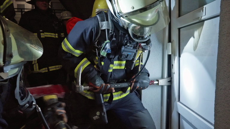 Ein Feuerwehrmann öffnet eine Wohnungstür mit speziellem Gerät