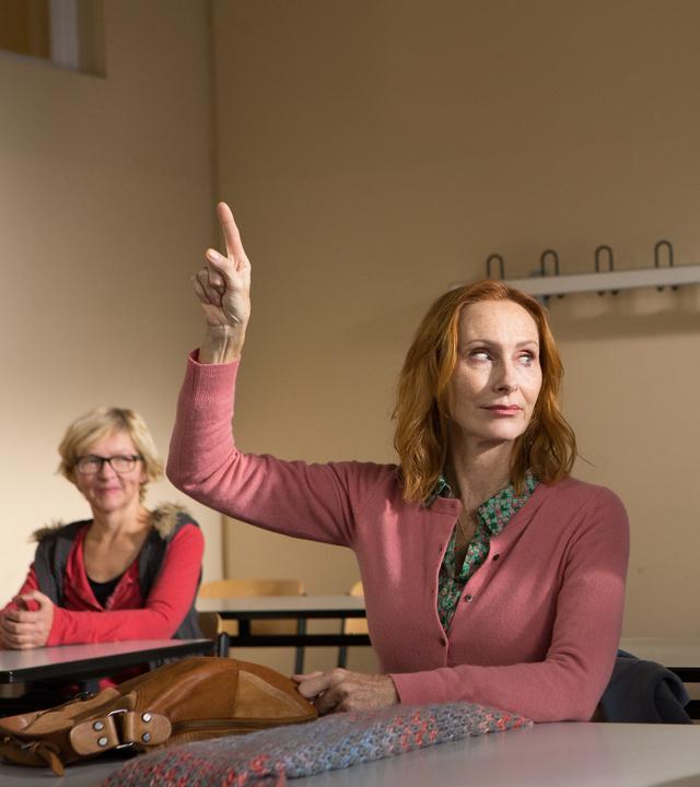 Gundula (Andrea Sawatzki und Gerald (Axel Milberg) sitzen in einem Klassenraum und Gundula (Andrea Sawatzki) meldet sich.