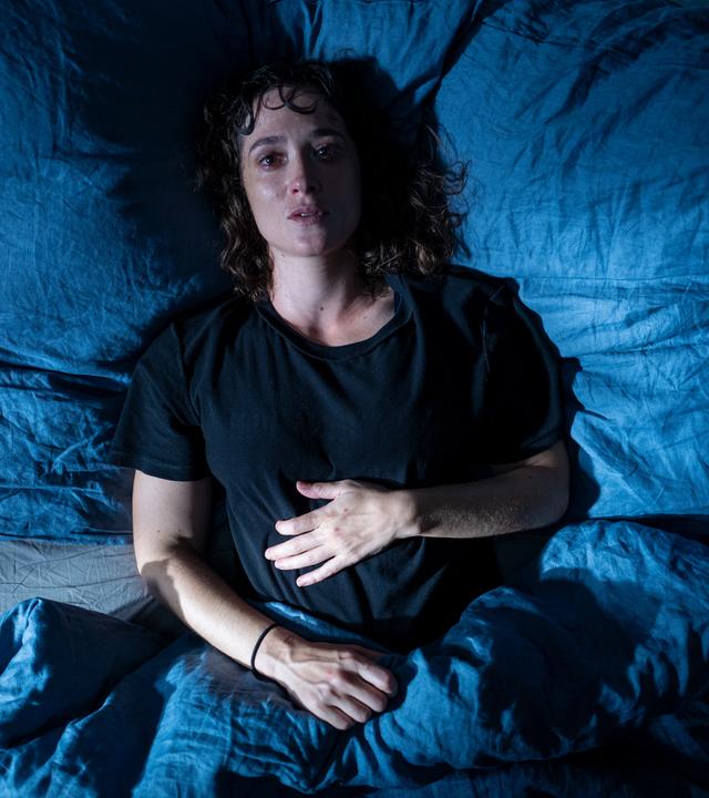 lick von oben: Katja (Friederike Becht) liegt nachts betrunken in ihrem Bett und blickt in die Kamera. Sie sieht verschwitzt aus.