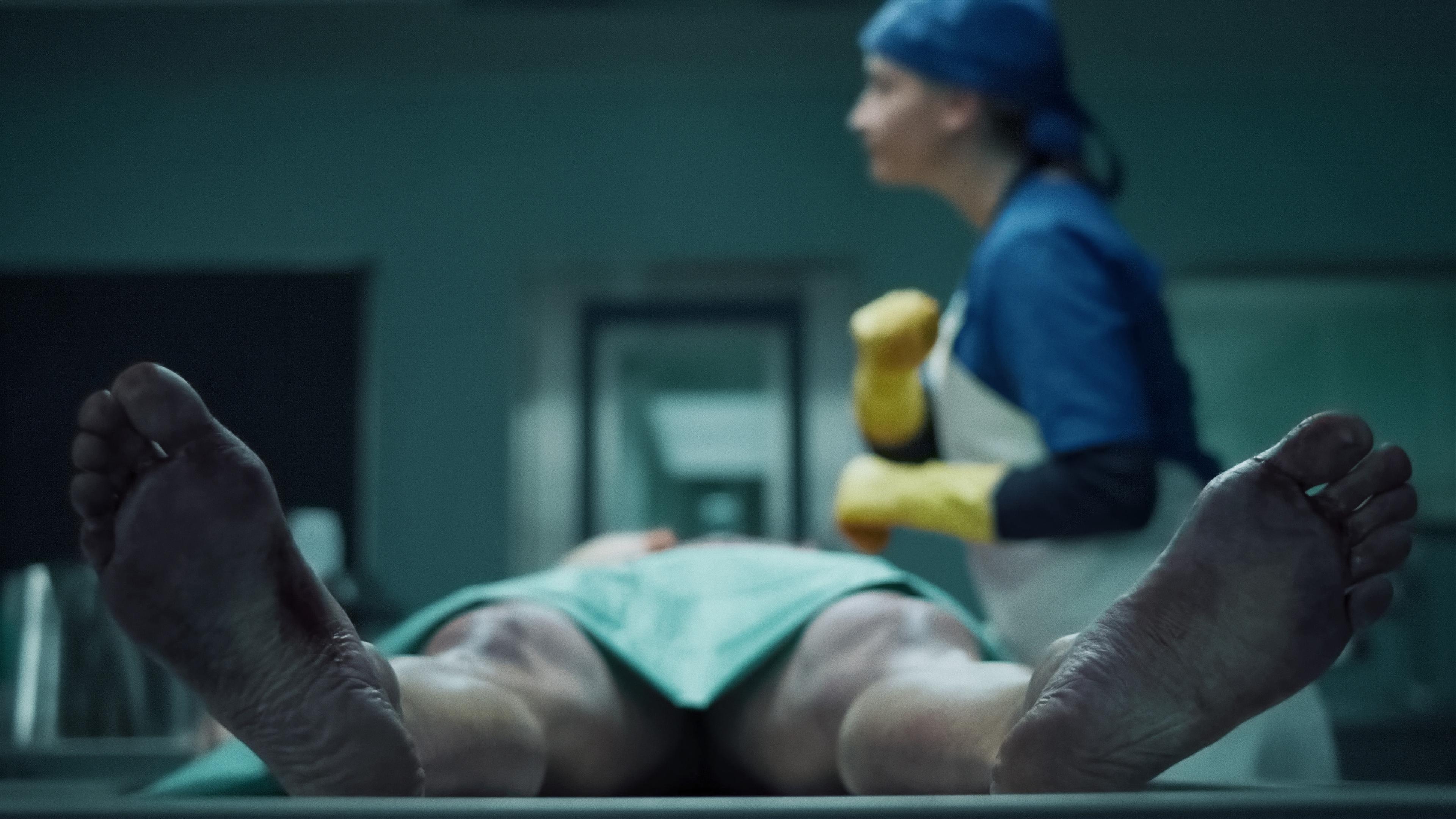 Eine Leiche liegt mit dem Rücken auf dem Obduktionstisch, während Theresa Wolff (Nina Gummich) in medizinischer Kleidung über sie lehnt. 