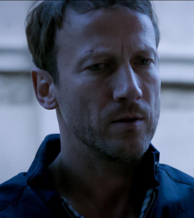 Benjamin Lietz (Wotan Wilke Möhring) steht vor einer Hauswand und schaut besorgt. 
