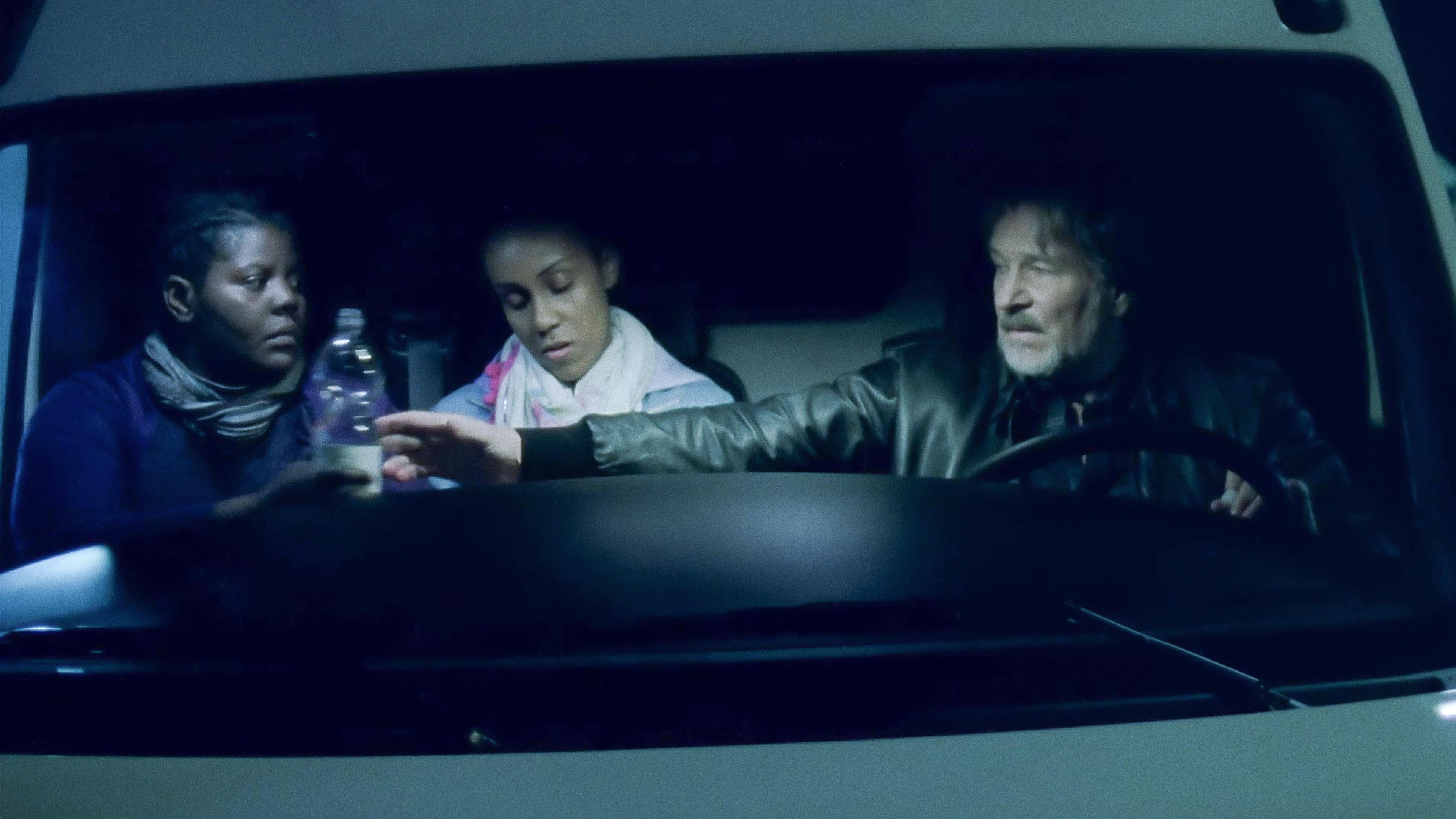 Die Fahrerkabiene eines weißen Lieferwagens: Am Steuer Bruno Markowitz (Götz George), auf den Beifahrersitzen Lola Obasi (Hadnet Tesfai) und eine weitere schwarz Frau.