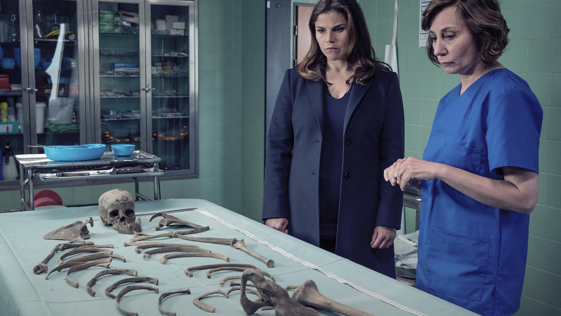 Kommissarin Nina Petersen (Katharina Wackernagel) und die Rechtsmedizinerin (Marina Weis) stehen an einem metallenen Tisch, auf dem ein menschliches Skelett liegt.