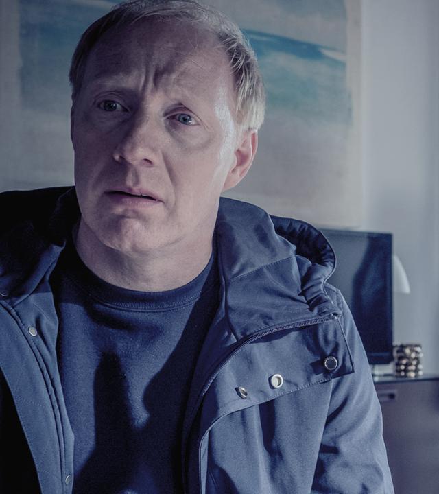 Peter Thies (Simon Schwarz), ein rotblonder Mann mittleren Alters, sitzt in seiner Wohnung und schaut verzweifelt. Im Hintergrund Nina Petersen (Katharina Wackernagel) und Karl Hidde (Alexander Held)