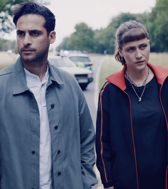 Karim Uthman (Karim Günes) und Jule Zabek (Sophie Pfennigstorf) stehen auf einer Landstraße. Hinter ihnen ein verunglücktes Auto und ein Polizeiauto mit Blaulicht. Beide schauen nachdenklich nach vorn.