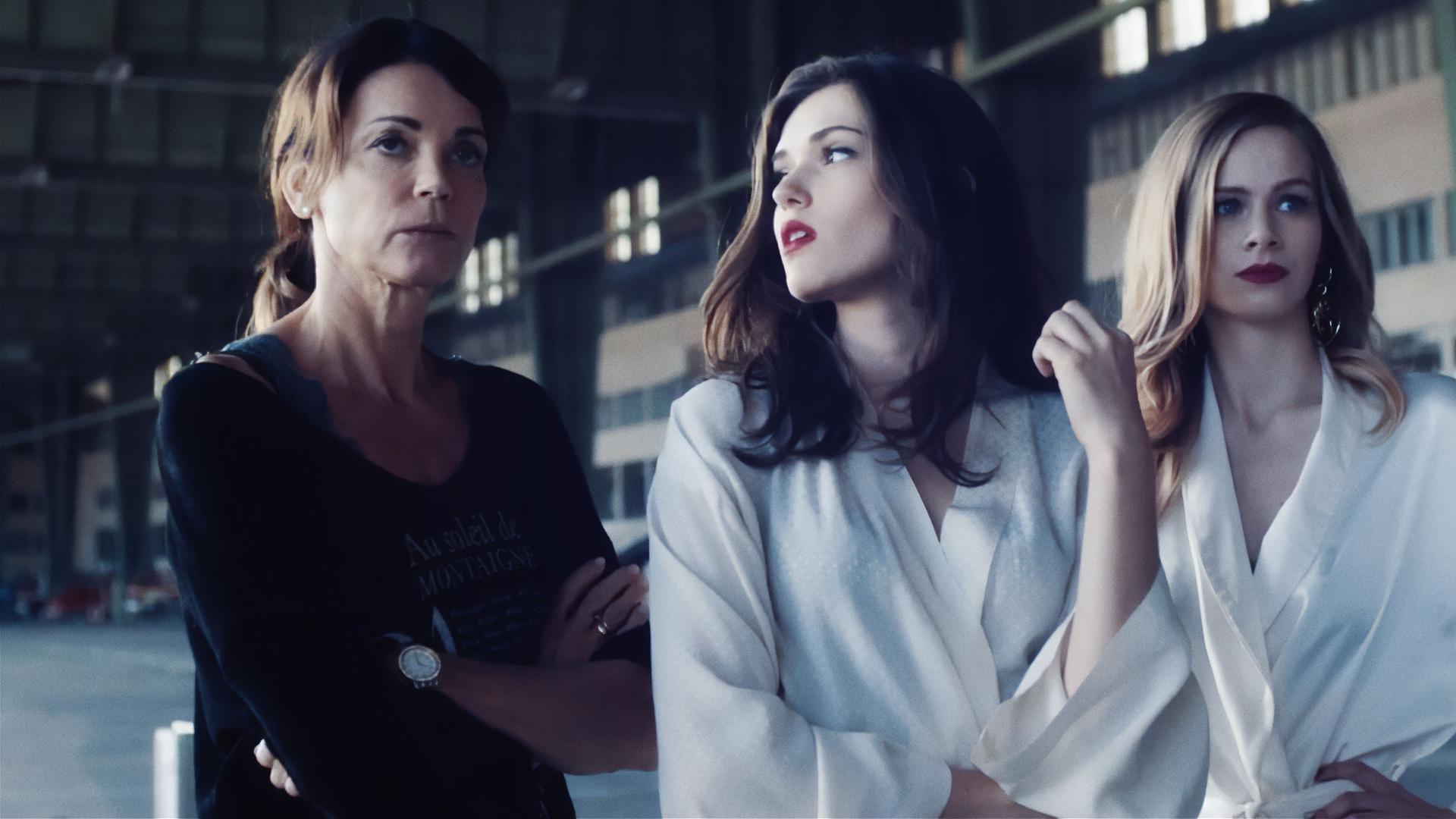 In einer industriellen Halle stehen drei Frauen und schauen genervt: Helen Weber (Gerit Kling), Hanna Weber (Caroline Hartig) und Leonie Seiters (Amelie Otto). Hanna und Leonie haben beide auffällig rot geschminkte Lippen und tragen weiße Morgenmäntel - offenbar sind sie als Models da.