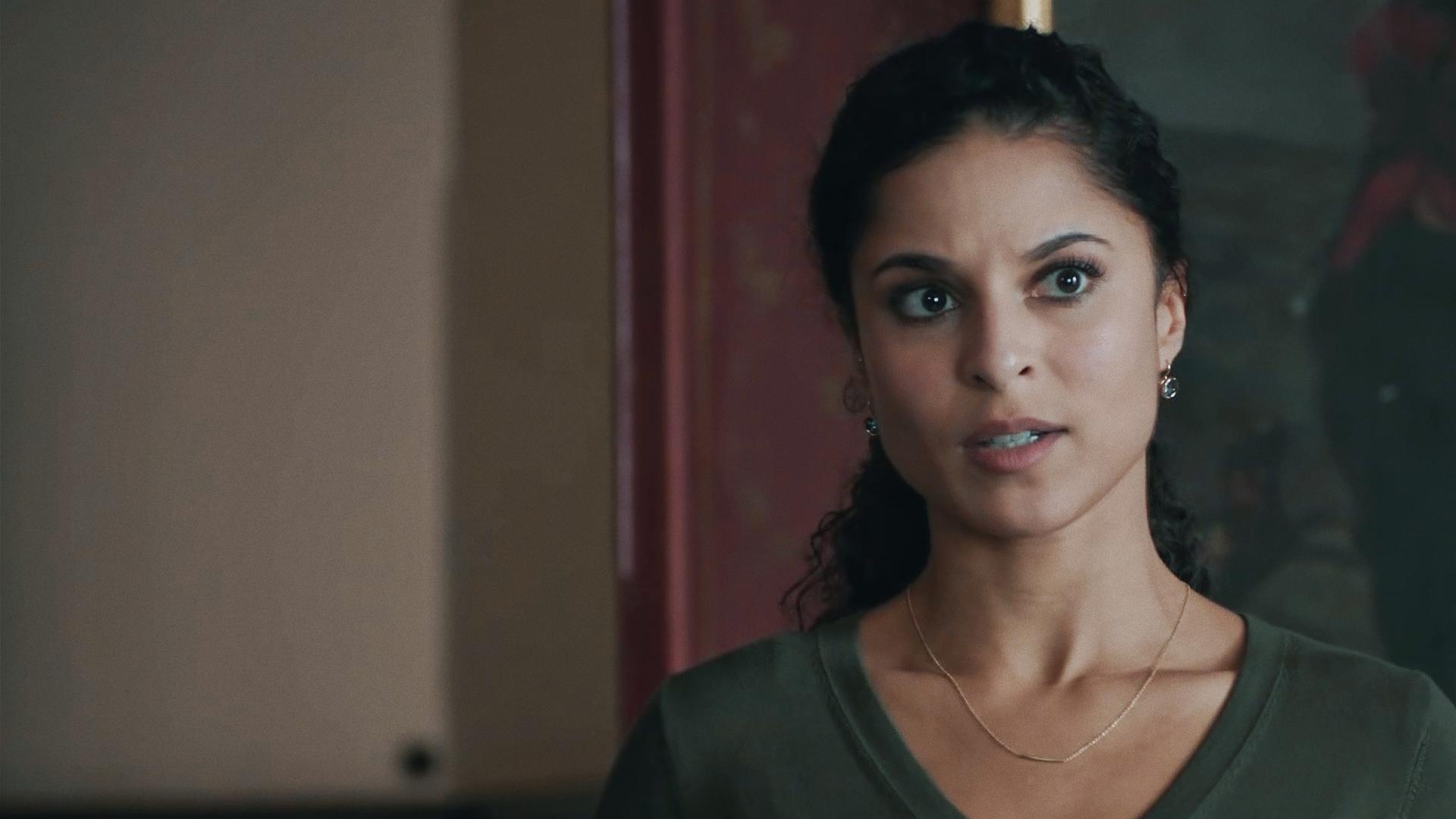 Tessa Tilker (Patricia Meeden) in einem Innenraum vor einem dunklen, kaum erkennbaren Ölgemälde. 